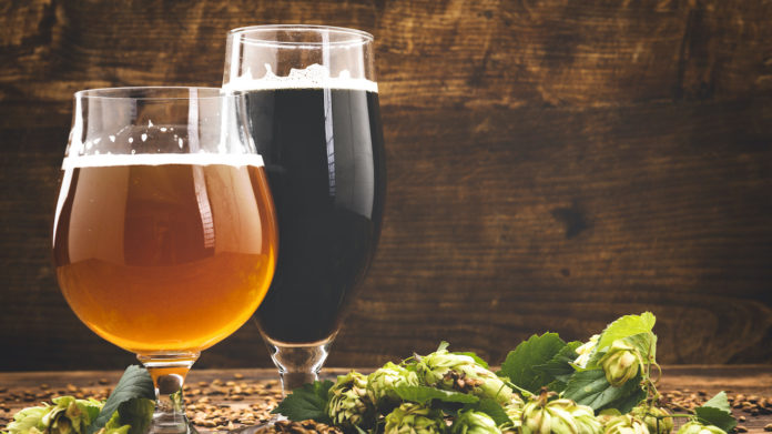 beer surrounded by hops on wooden background