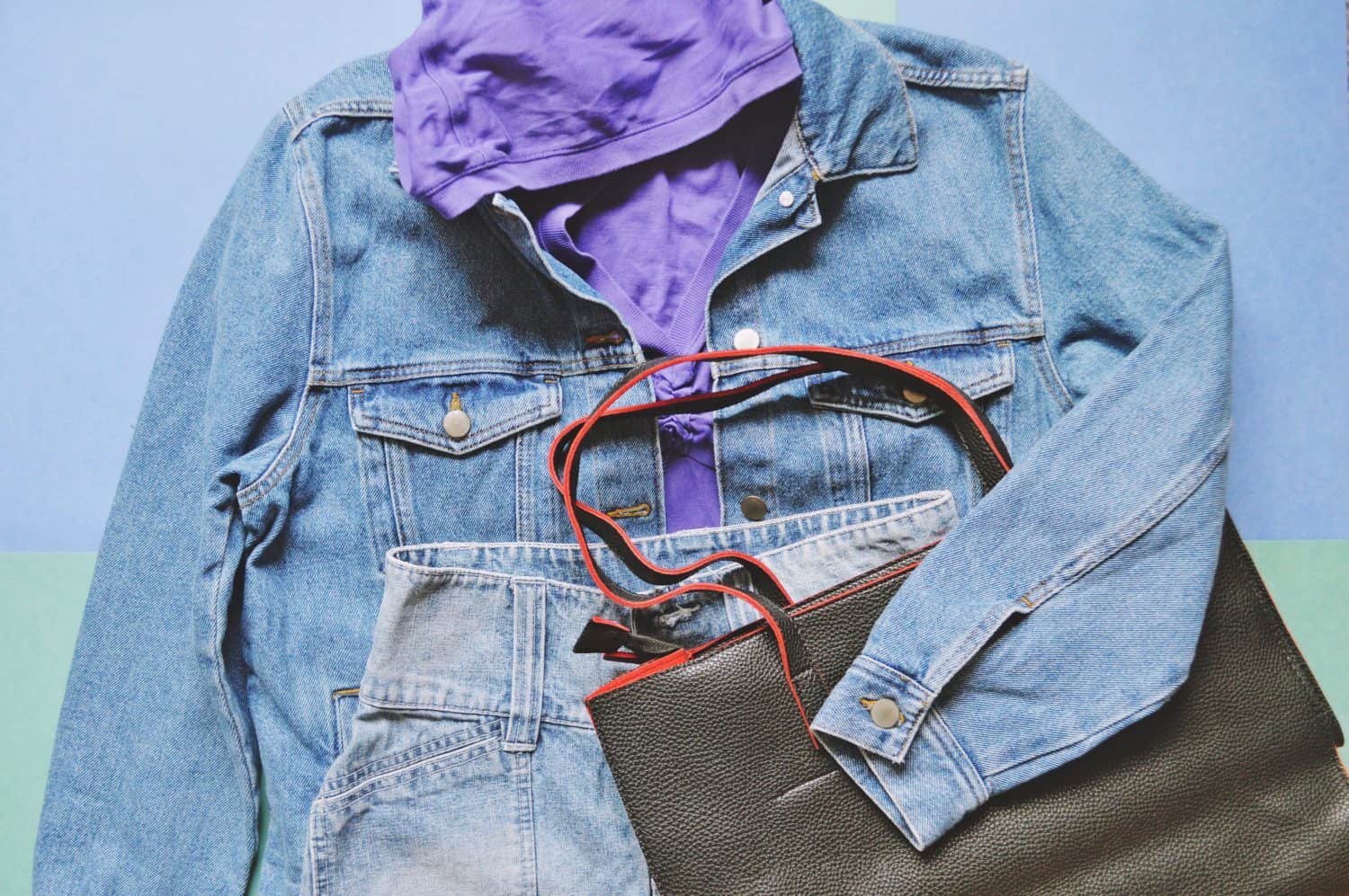 90s style fashion outfit. Purple hoody sweatshirt, blue denim jacket, cotton skirt and trendy bag. Fashionable summer women's clothes in the style of sports chic. Flat lay photo