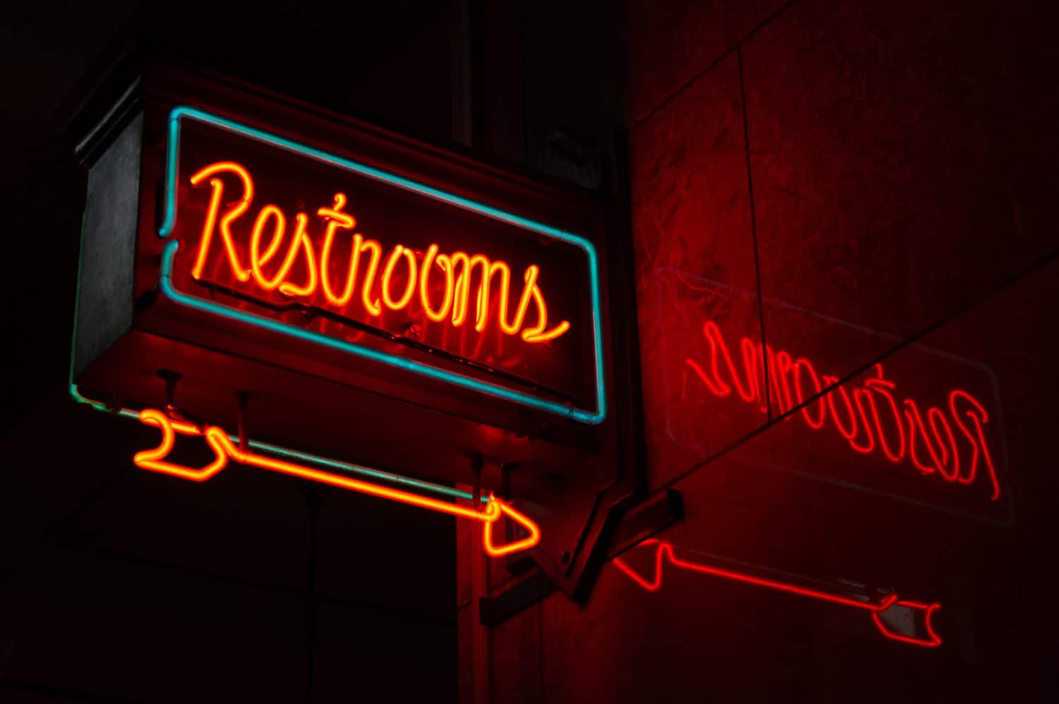 Neon restrooms sign with reflection