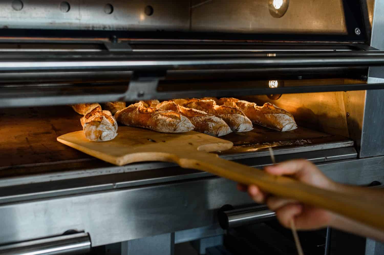 Freshly-baked baguettes being taken from oven