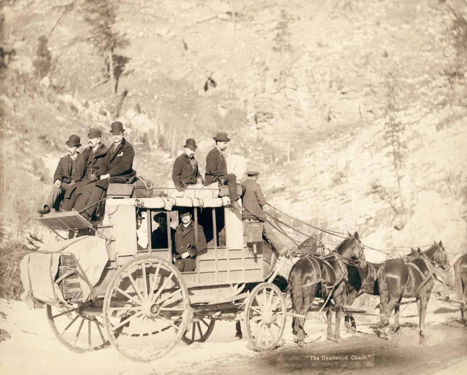 The Deadwood stagecoach fully loaded with nine formally dressed men sitting in and on top of coach, ca.1885.