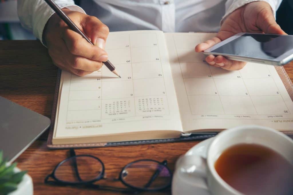 Planner plan Schedule Calendar and reminder agenda, work online at home. Women hand planning daily appointment and write business trip in diary at office desk. 2024 Calendar reminder event concept