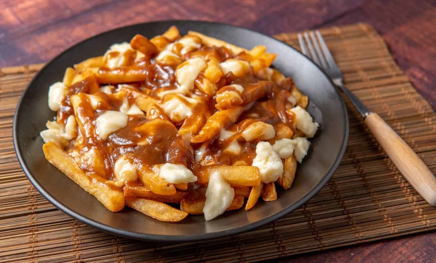 Delicious Poutine with cheese curds french fries on the table. so juicy and yummy