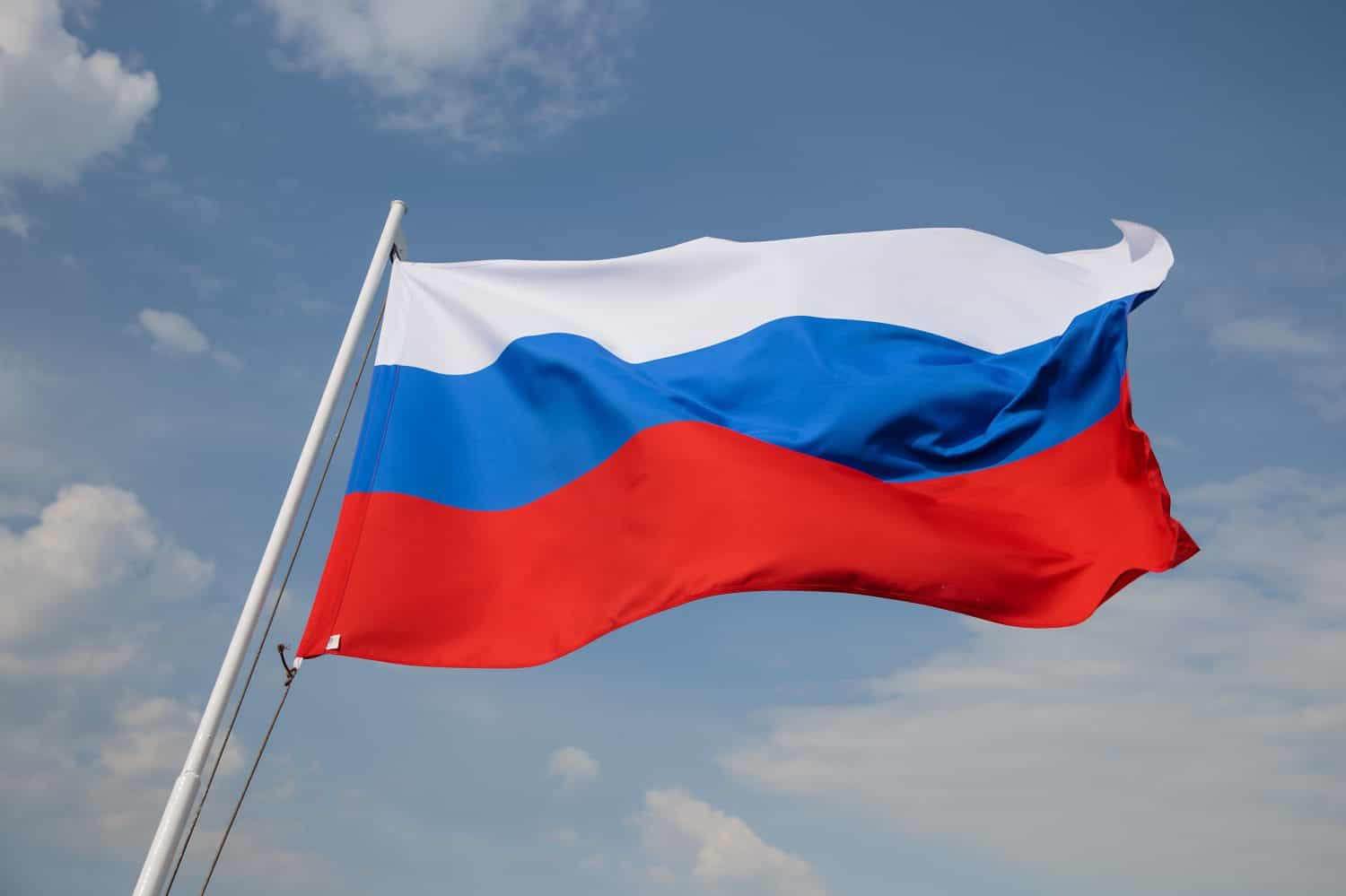 Russia flag is waving in front of blue sky.