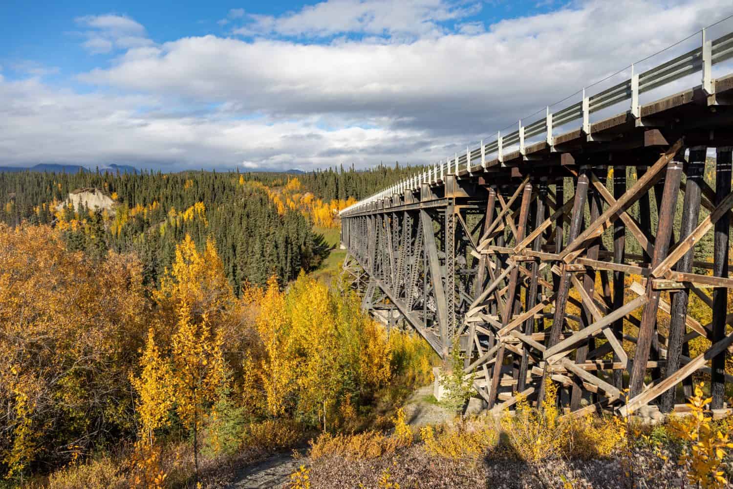 View of Kuskulana River Bridge in Wrangell St Elias National park with mountains and fall colors