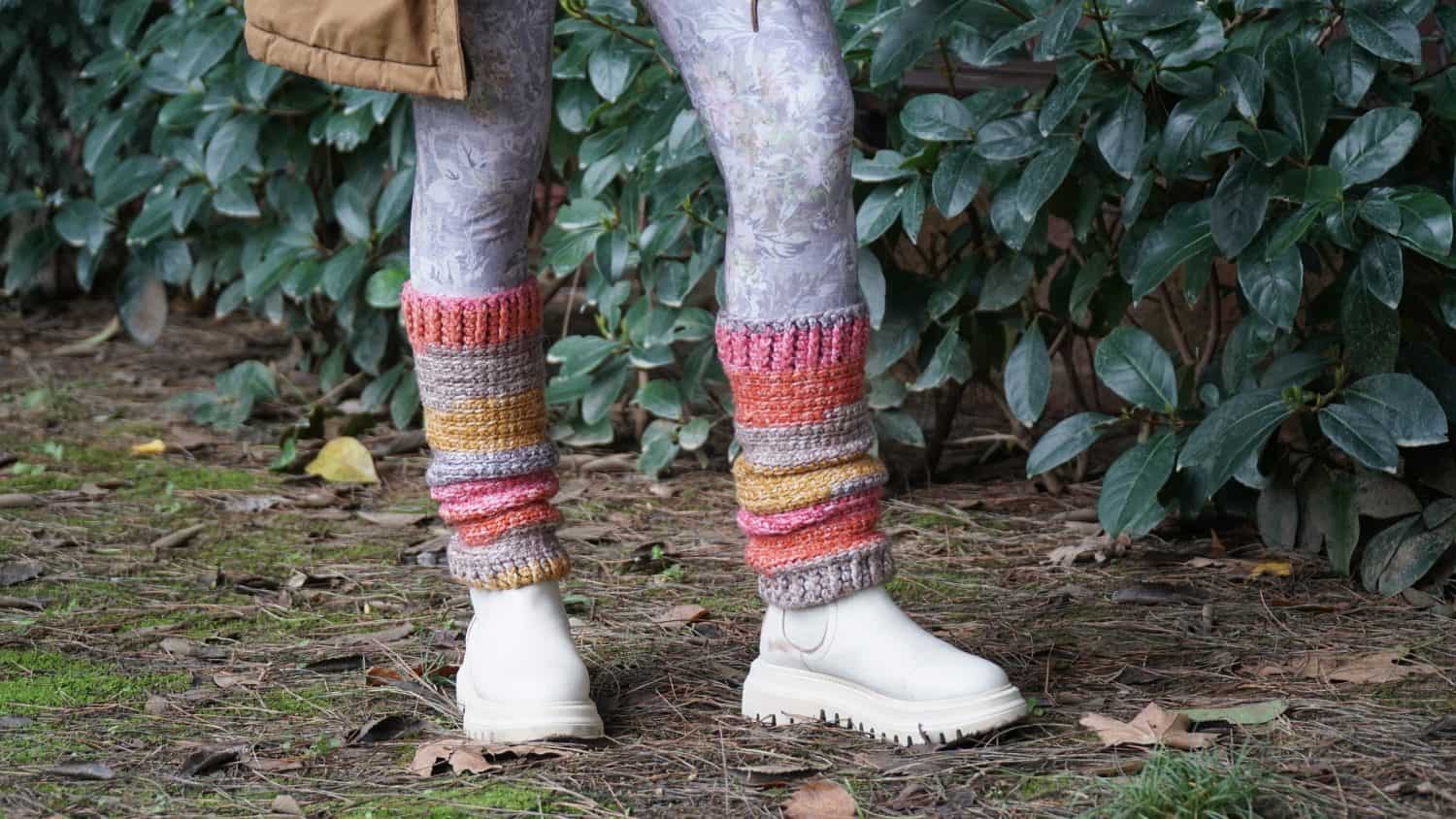 A girl with colorful crochet legwamers in a park.