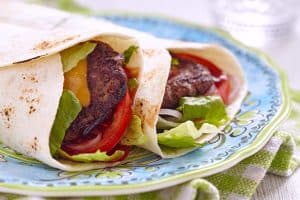 Fresh tortilla wrap with grilled beef burger and vegetables