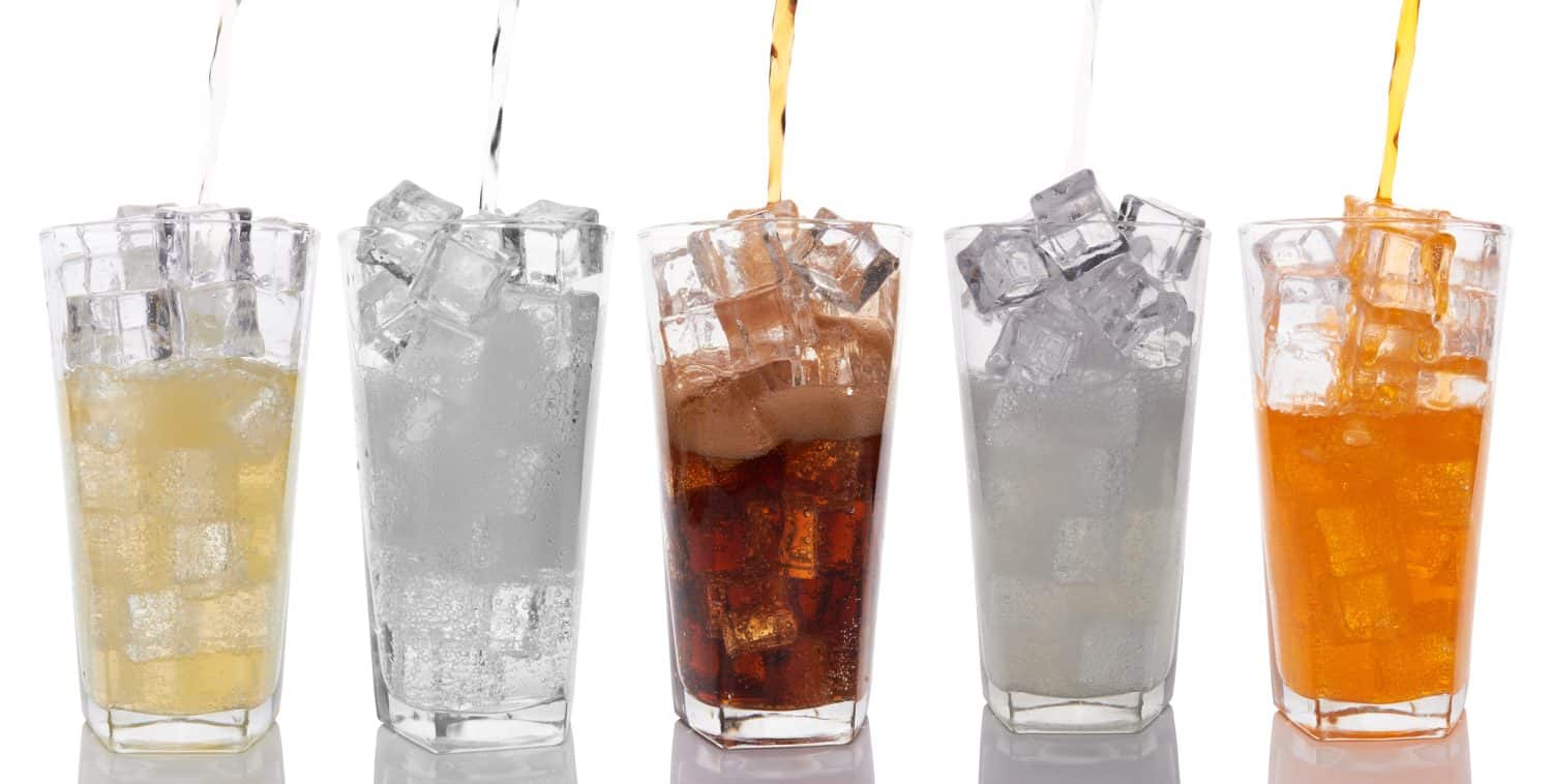 Glasses with sweet drinks with ice cubes isolated on white