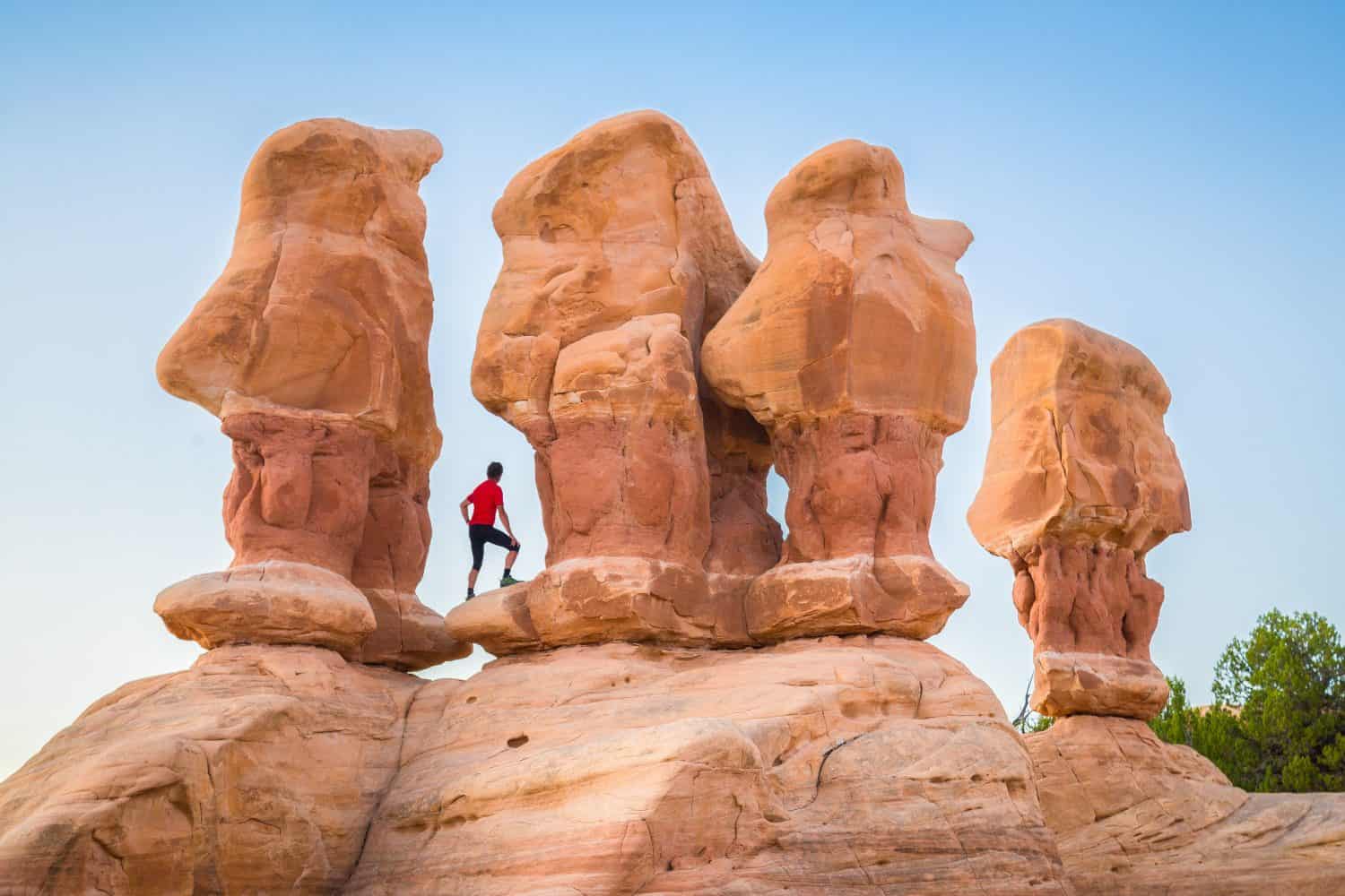 Beautiful view of male hiker standing between amazing Four Hoodoos sandstone formations in Devil's Garden in beautiful evening light at sunset, Grand Staircase-Escalante National Monument, Utah, USA