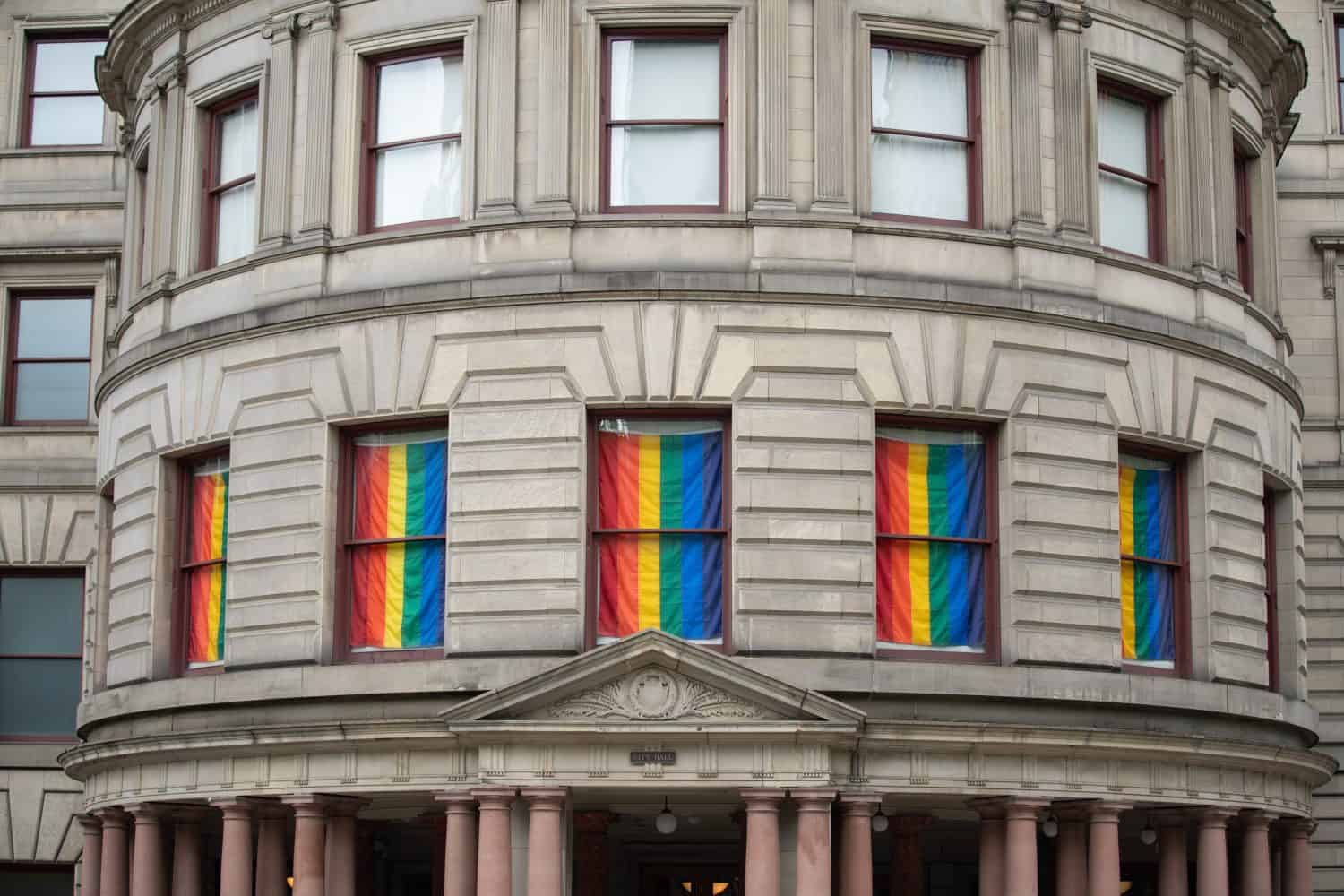 Portland city hall building with windows draped in LGBTQ rainbow flag.