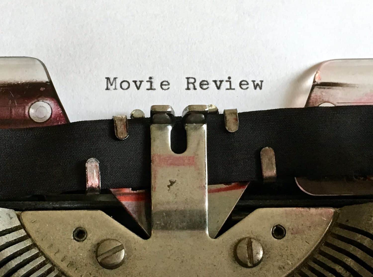 Movie Review, heading title typewritten on white paper in black ink on vintage manual typewriter machine