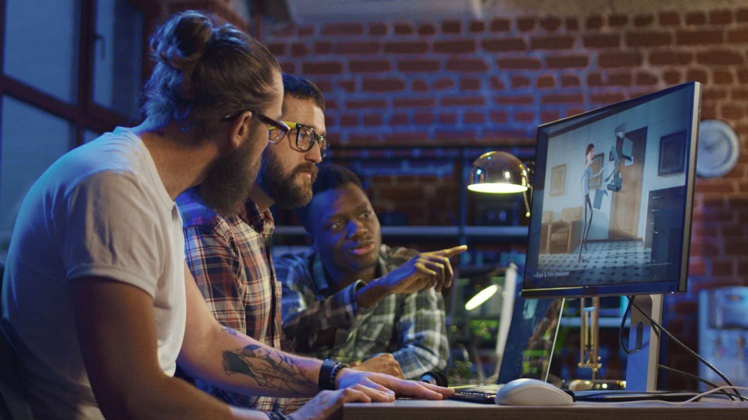 Side view of diverse group of men sitting at table with computer and coworking on creation of new cartoon