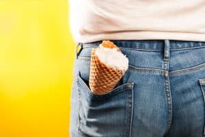 ice cream cone in jeans pocket on yellow background