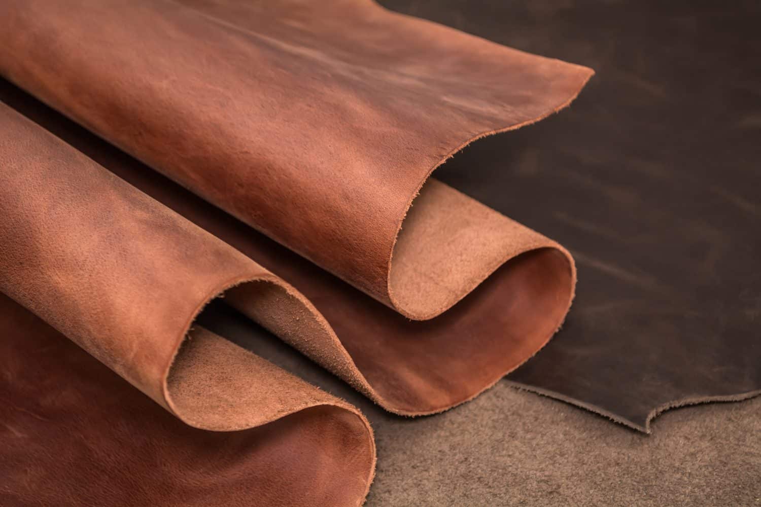 Rolls of natural brown and black leather. Materials for leather craft