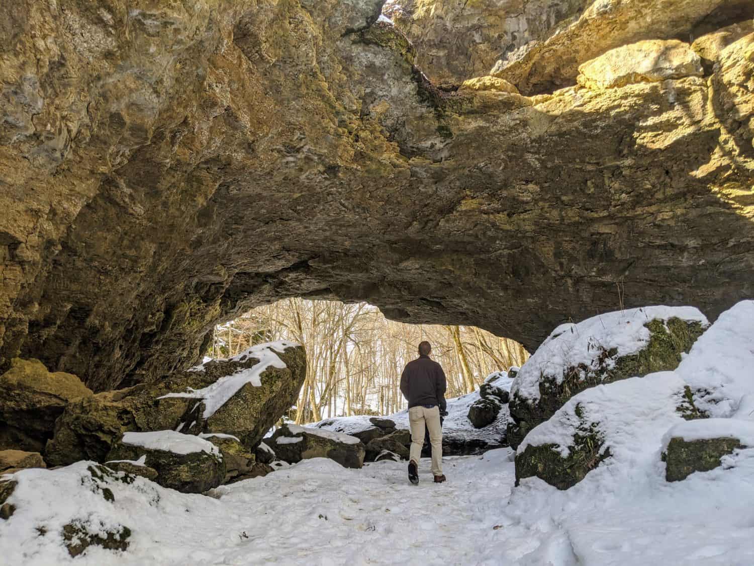 Man Hiking in Winter Snow at Maquoketa Caves State Park, Iowa- Natural Stone Land Bridge