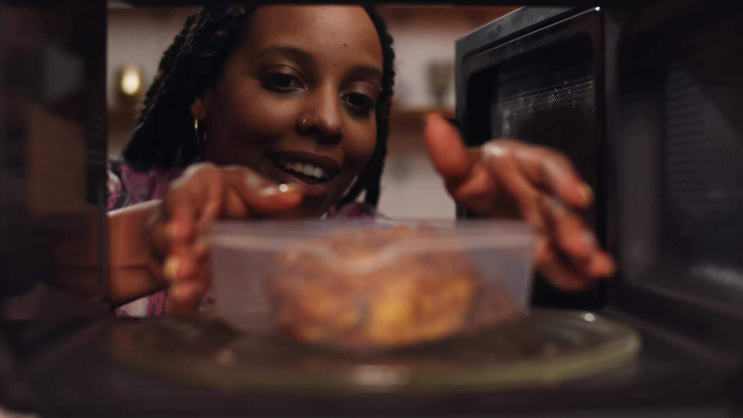 Woman using the microwave oven to heat food