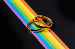 Gold rings for lesbian and gay wedding and rainbow ribbon on black table