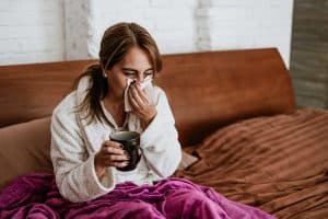 latin ill adult mature woman sneezing and using napkin for flu on bed at home in Mexico Latin America
