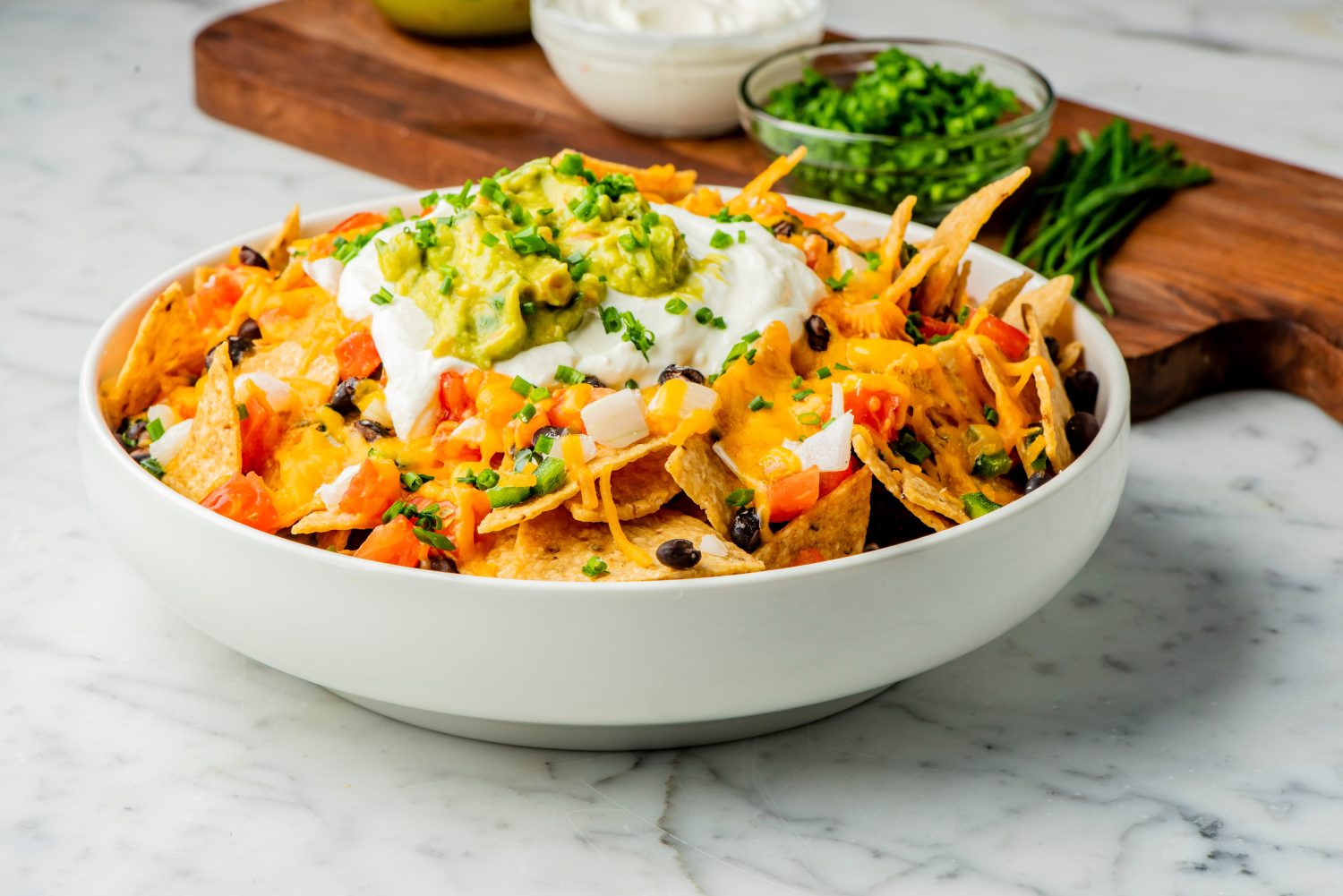 Nachos. Crispy tortilla chips topped with melted cheddar cheese, salsa, black beans, jalapenos, guacamole, sour cream and lettuce. Tex-Mex or Mexican restaurant classic traditional menu item.