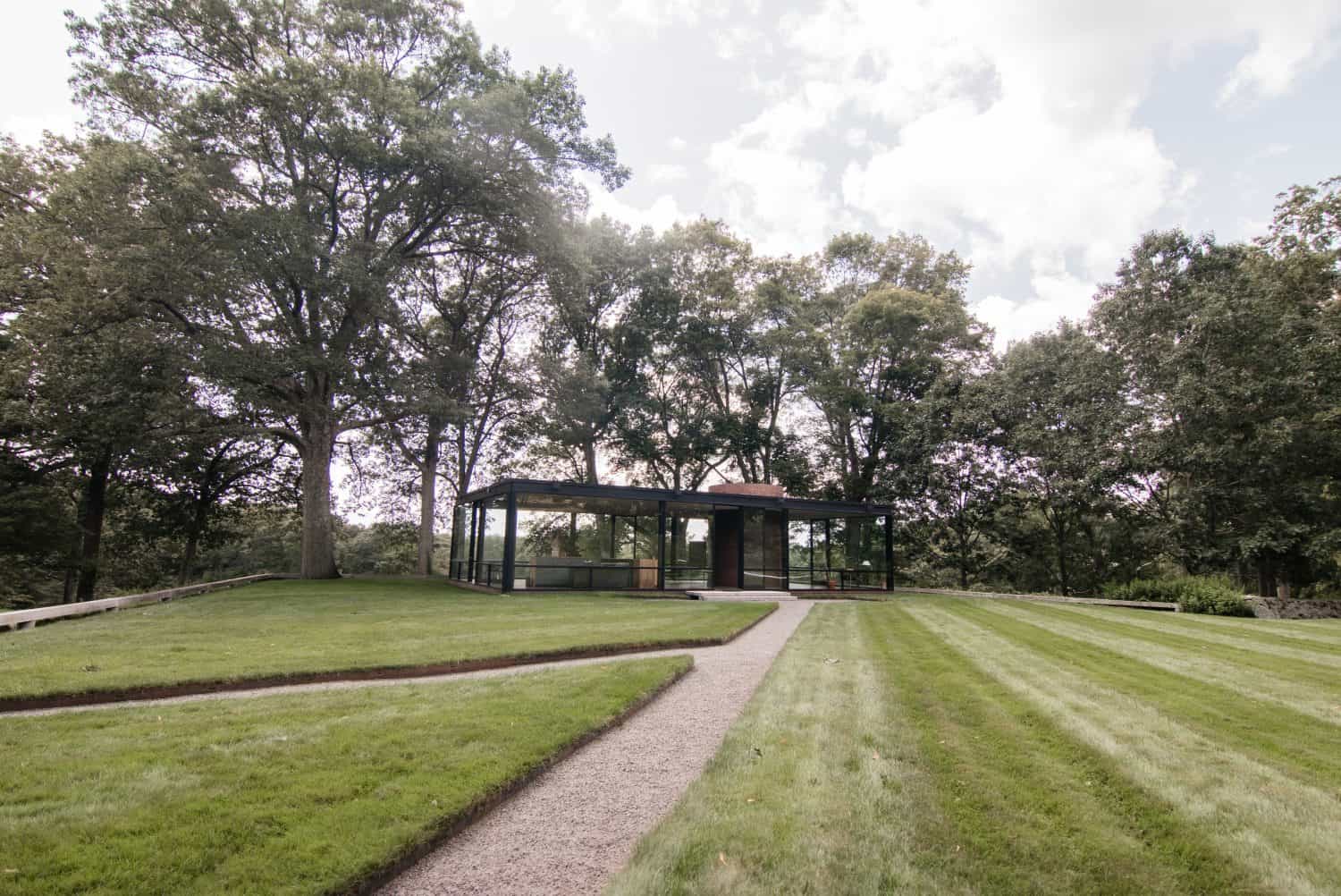 Exterior of Philip Johnson's glass house in New Canaan, CT. Bright photo with a lot of green. No people in photo.