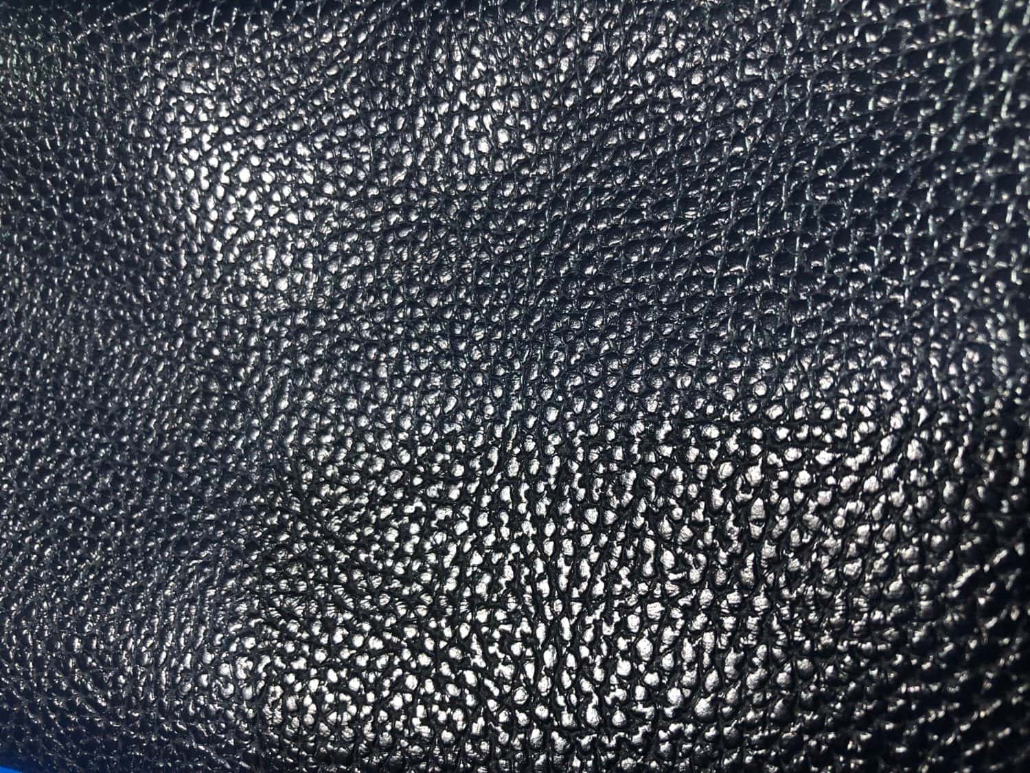 Black PU leather used for making bags in various styles. There are many colors. It has a shiny, rough surface. But it is soft, not hard, and feels like real cowhide to the touch.