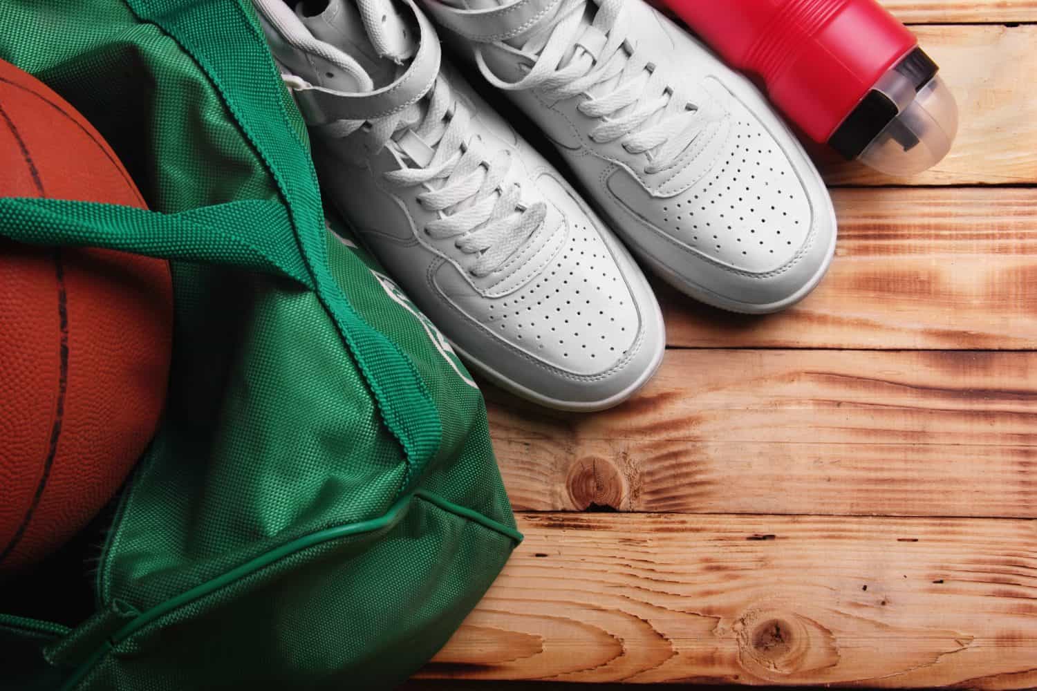 High white sneakers , Sport bag Basketball ball inside the bag, bottle with .Top of white background down wooden background..Concept basketball training free space.Selective focus ball defocused