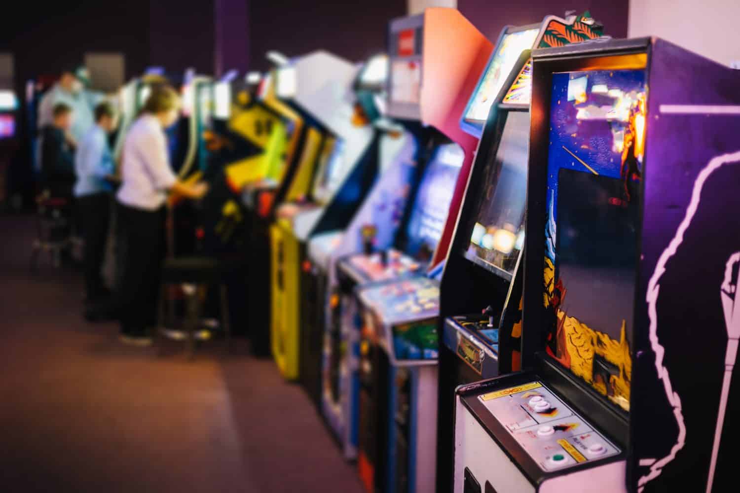 Old Vintage Arcade Games in a dark room and players playing video games in the background