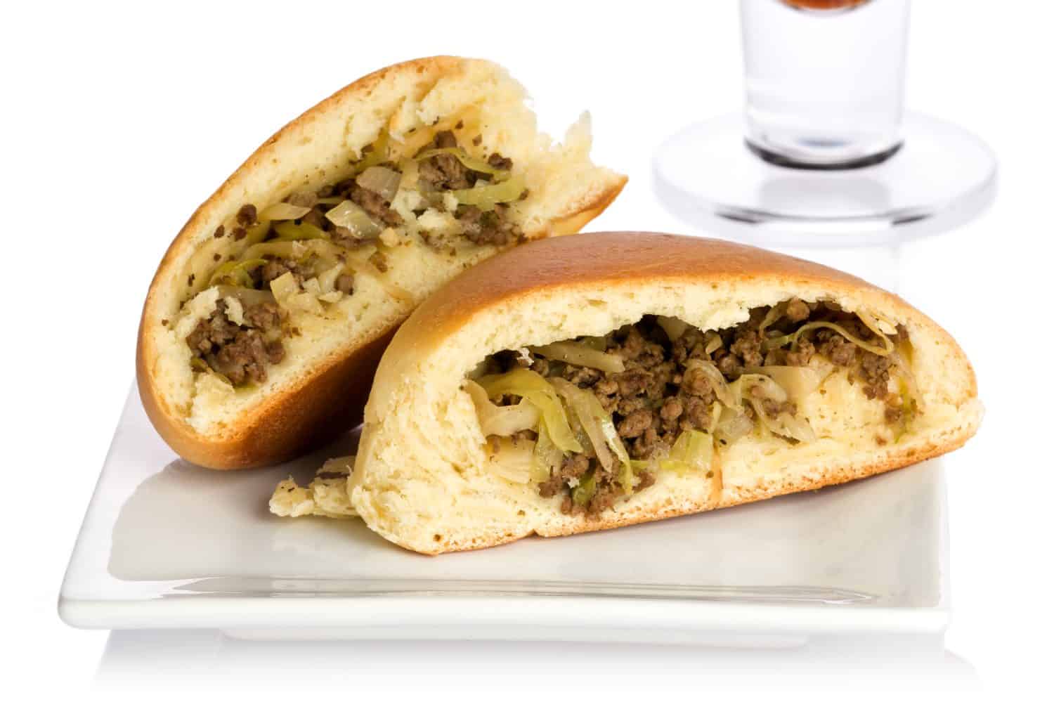Single sliced bierock with seasoned ground beef, cabbage, and onion filling on a small plate.