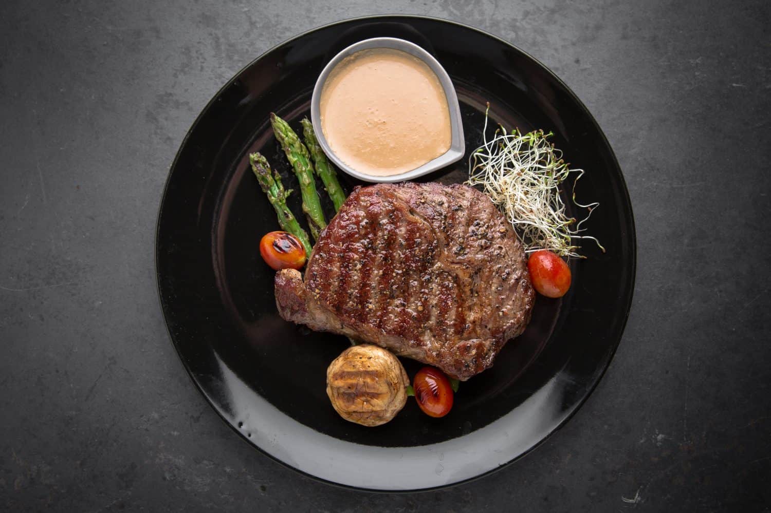 Beef steak with spices, grilled vegetables, asparagus and cream sauce. Gourmet dish