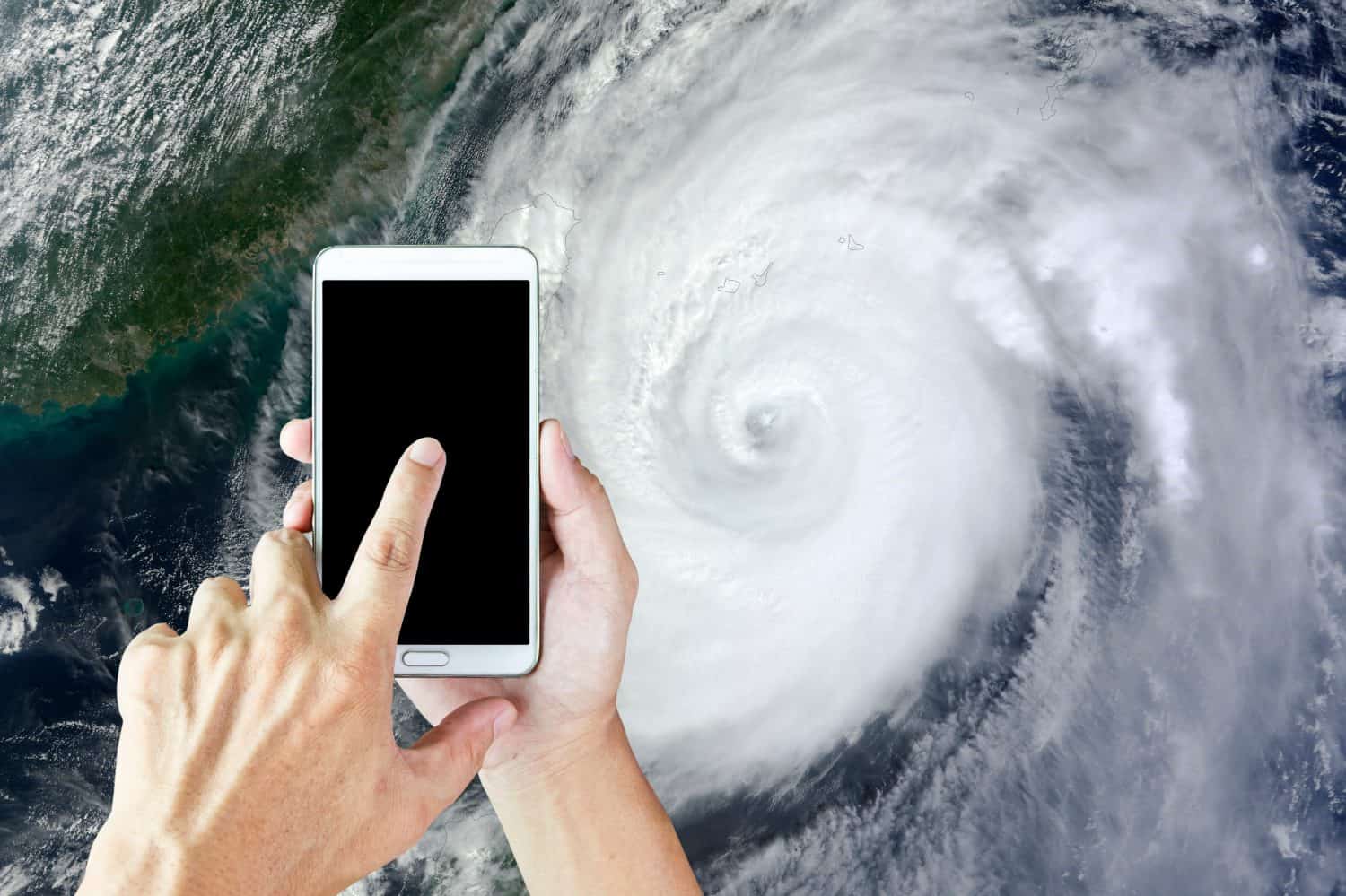 Man use mobile phone, image of a storm as background.(Element of this image furnished by NASA)
