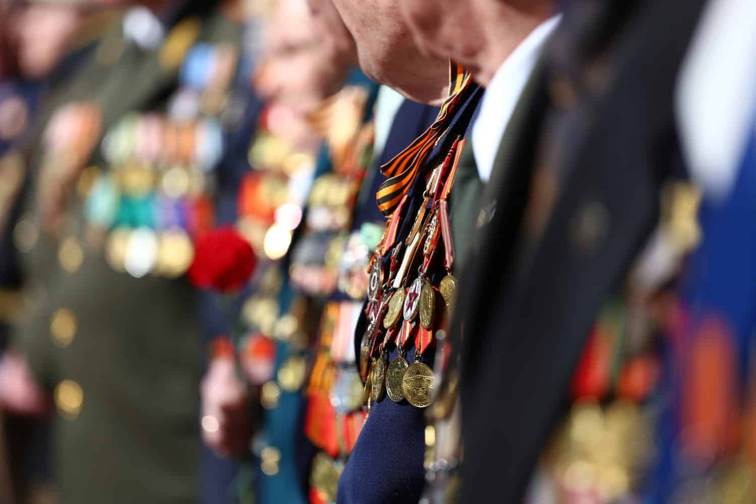 Patriotic holiday in honor of the anniversary of the end of the war, veterans are congratulated, the old soldiers with a lot of medals and orders are holding flowers, the memory of the dead