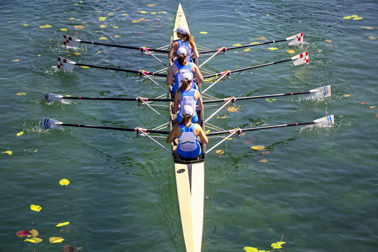 Women's quadruple rowing team on turquoise green lake