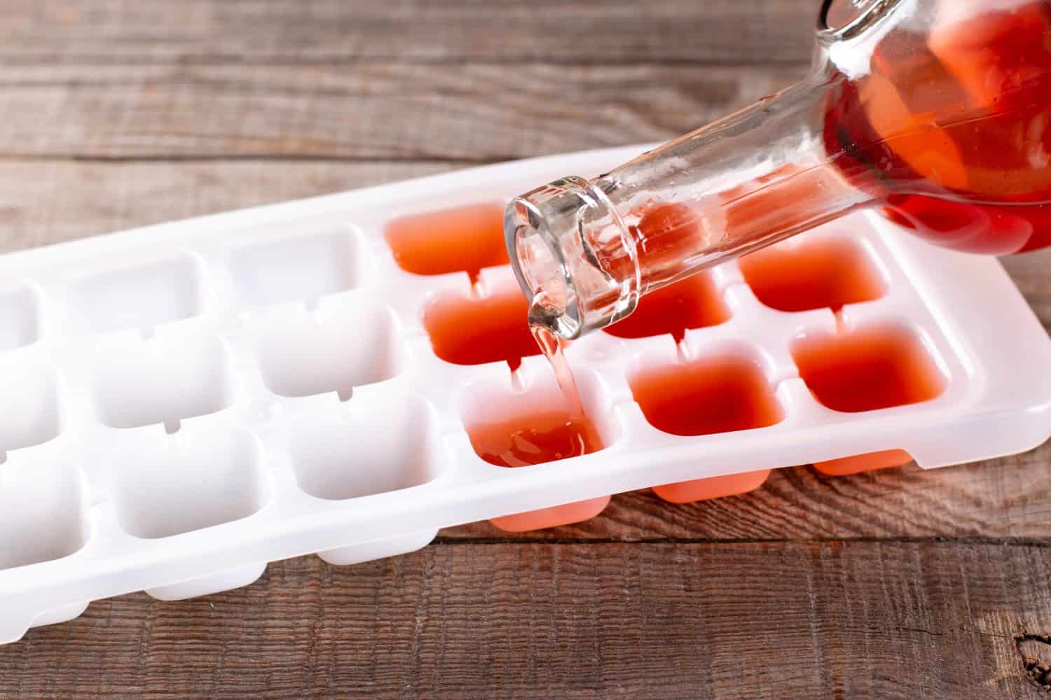 Pouring wine in ice cube tray on a wooden table