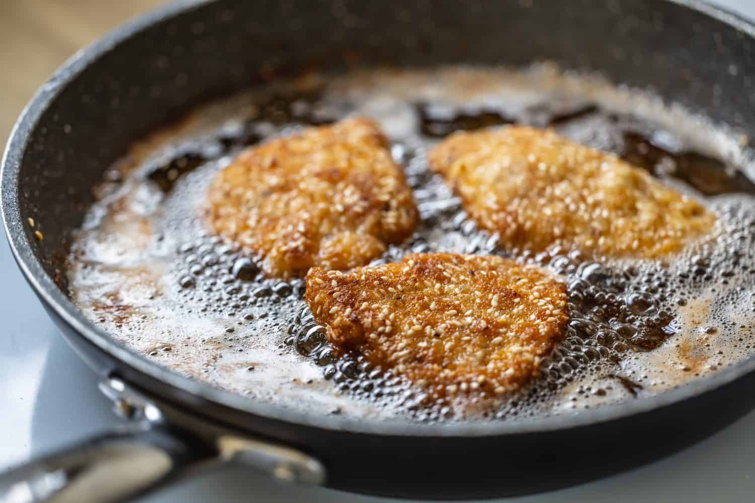 Breaded schnitzels are frying in a sizzling pan making the traditional vienese food.