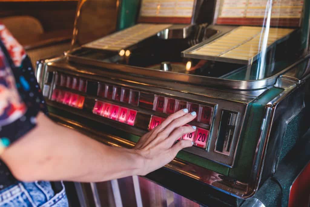 Vintage American music jukebox with illuminated buttons, process of choosing song composition, retro old-fashioned juke-box with vinyl discs musical box machine in cafe diner restaurant