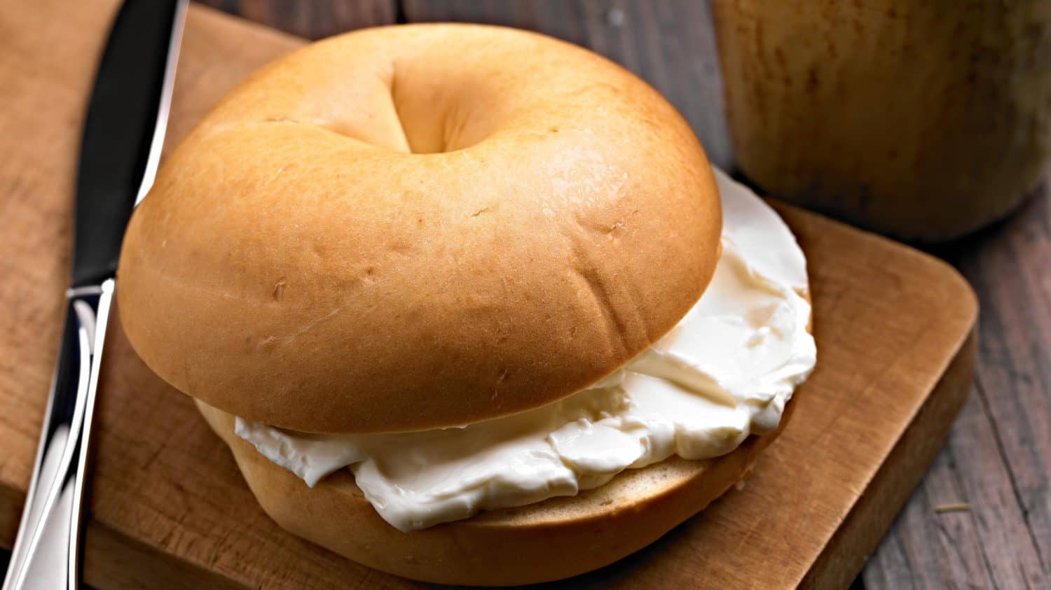 Savory Delights: Close-Up of Cream Cheese-Spread Bagel on a Delectable Food Background in Stunning 4K