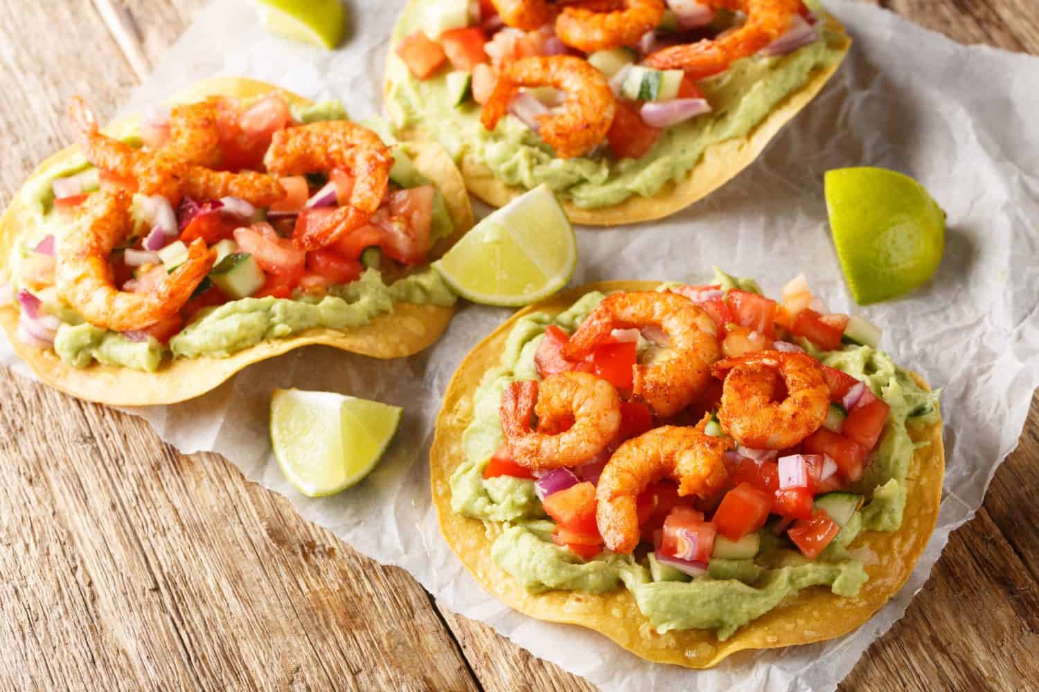 Tostadas with shrimps, tomato salsa and guacamole close-up on a wooden table. Horizontal