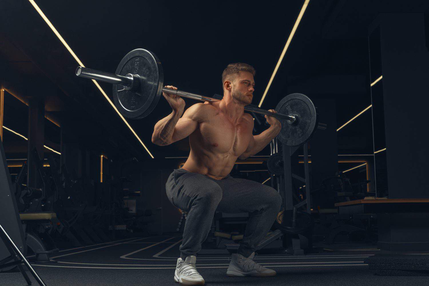 Muscular man doing squats with barbell in a gym. Male bodybuilder doing workout Confident young man doing barbell workout in gym Powerful attractive man.