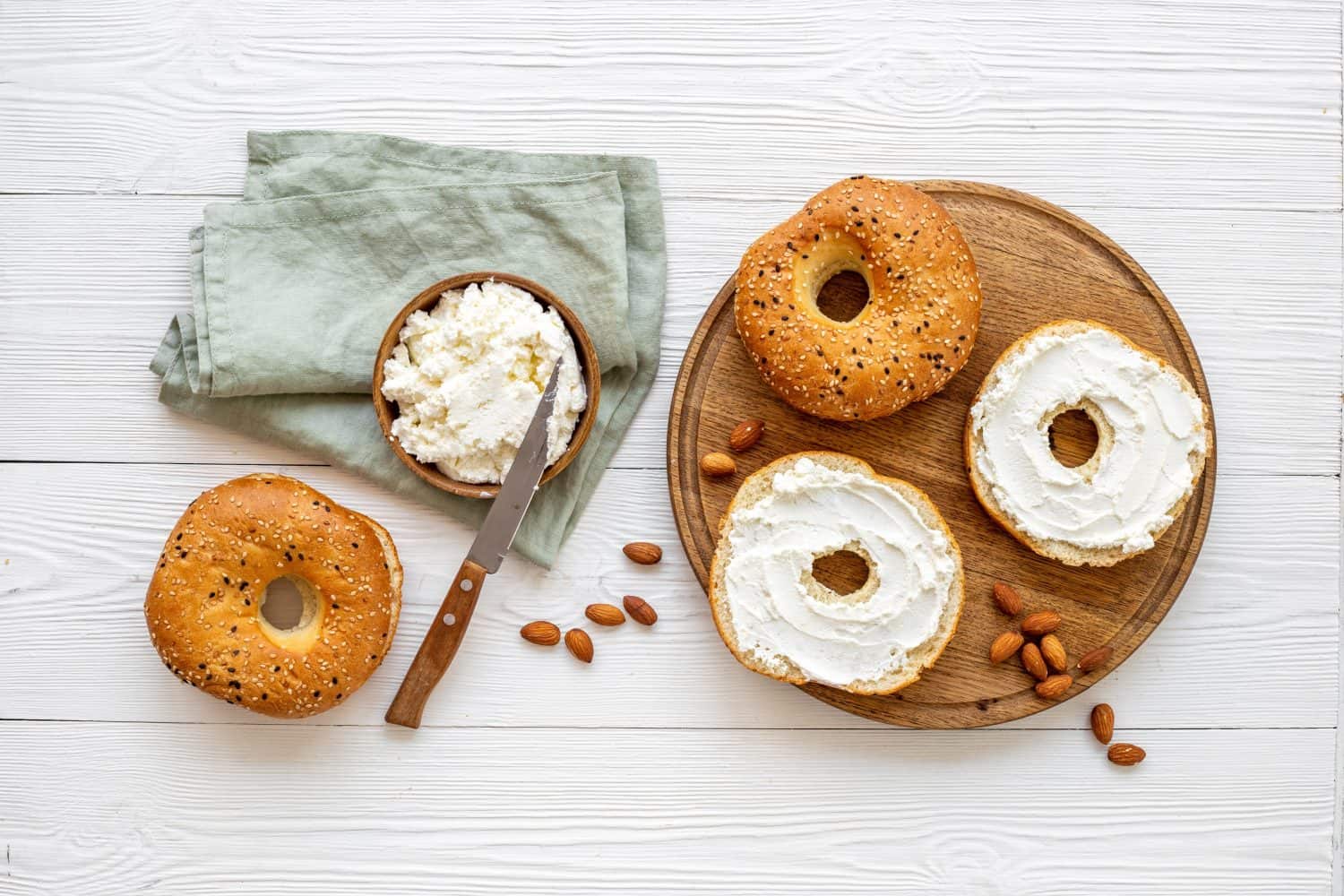 Fresh baked bagels with cream on board, top view. Healthy breakfast background.