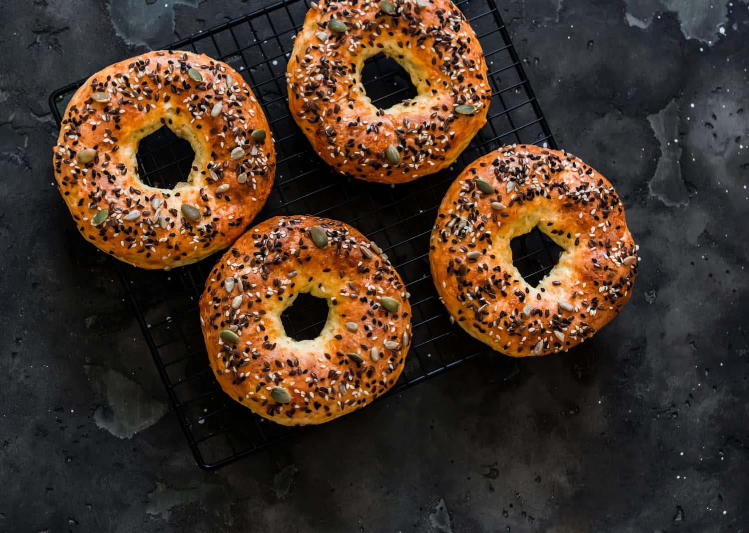 Quick bagels of cottage cheese and cheese on a baking sheet on a dark background, top view