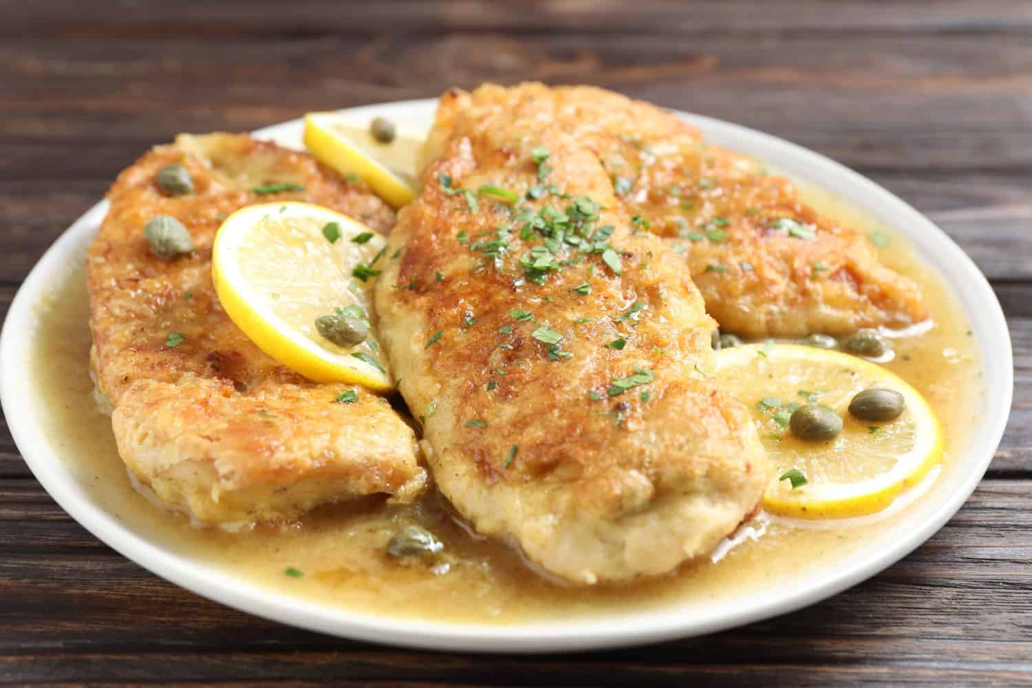 Delicious chicken piccata on wooden table, closeup
