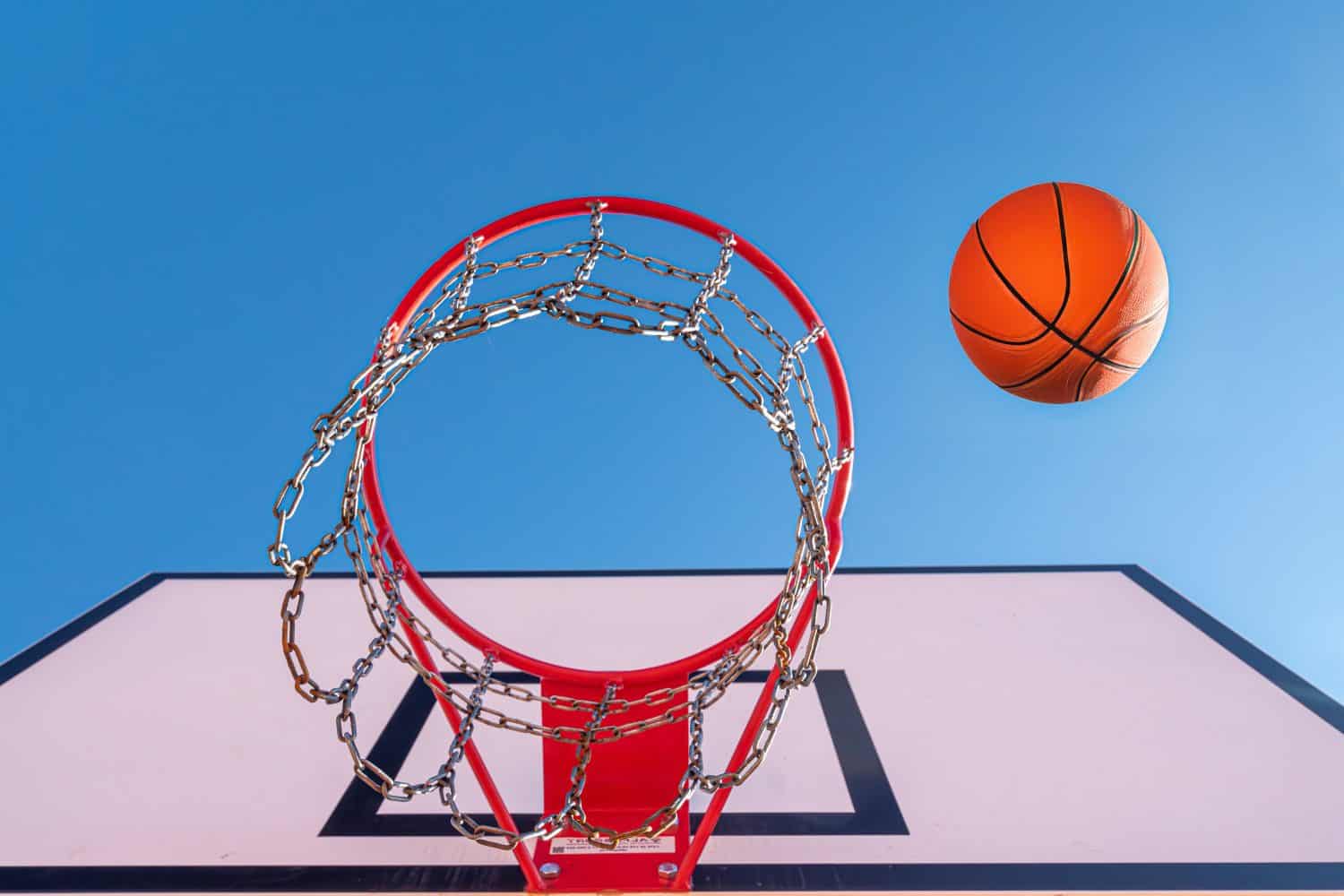 Used orange basketball with basket in background. Basketball street court stock photo