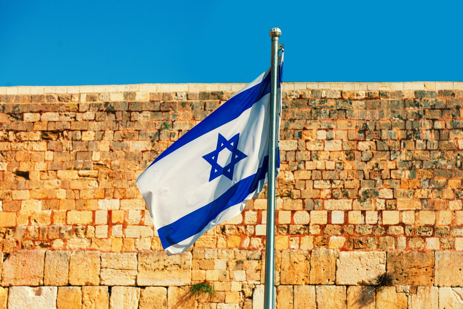 Israeli flag fluttering against Western wall in Jerusalem in Israel