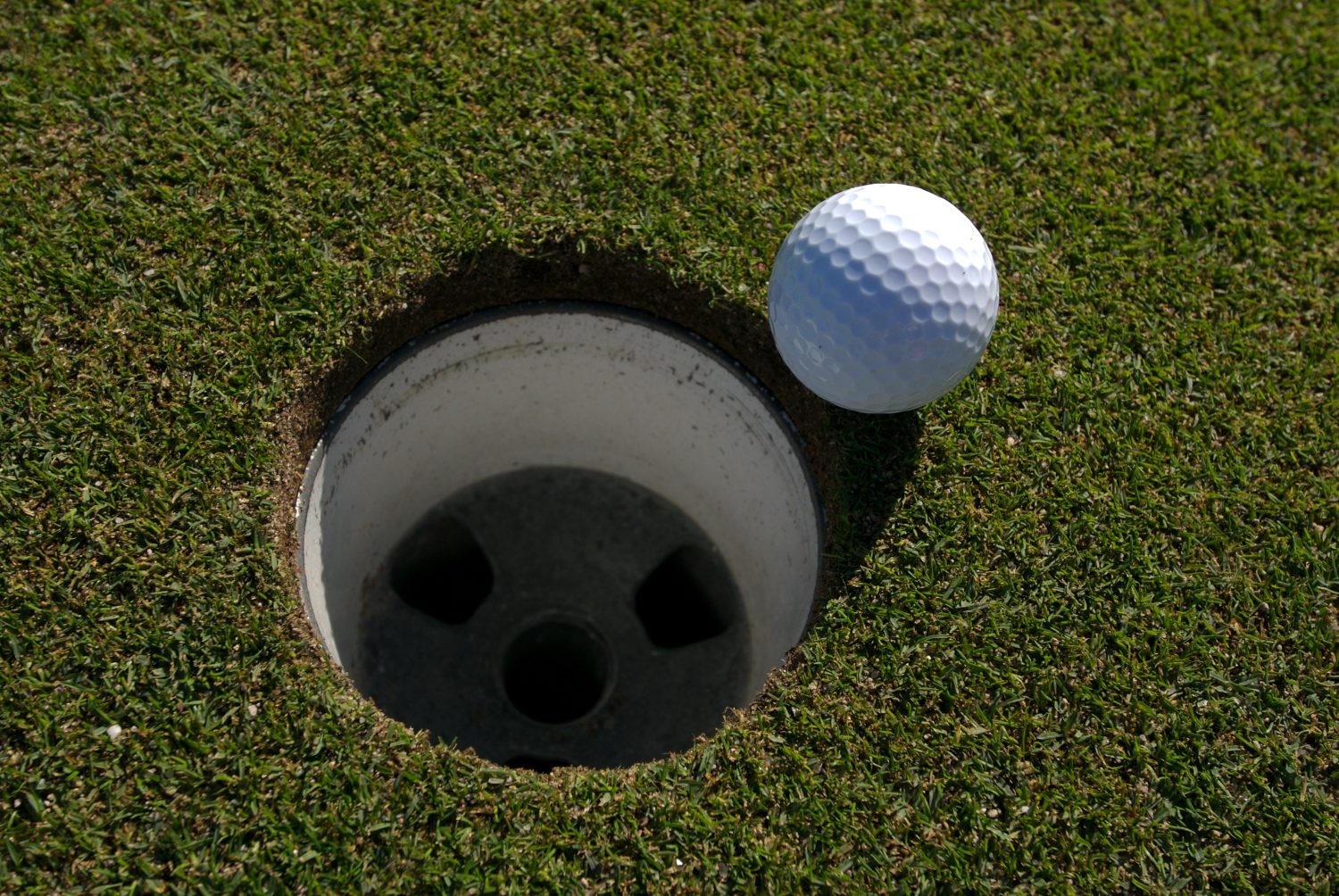 Overhead view of golf ball next to hole