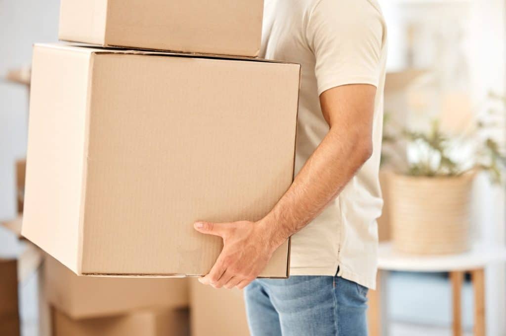 Man, relocation and moving with boxes in arms, property investment and real estate for new home. Tenant, asset packages and rental loan or mortgage, residential apartment and carrying cardboard