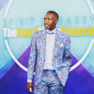 An image of pastor Uebert Angel wearing a blue suit speckled with various colors.
