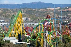 Wide view of colorful roller coaster rides at an amusement park, sunny day mountains in background. Six Flags Magic Mountain Six Flags Hurricane Harbor