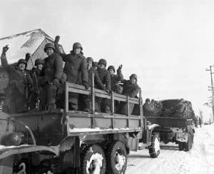 A happy group of American soldiers wave "goodbye" as they leave assembly point, first departure point, on a trip home.