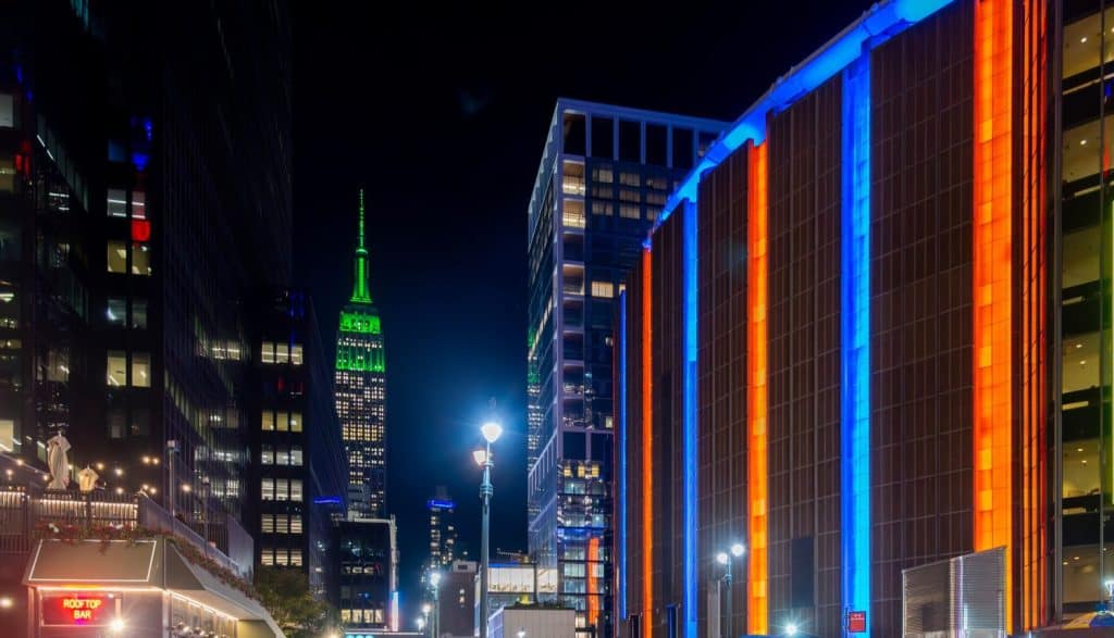 Madison Square Garden with the Empire State Building on the background at night. New York City, USA