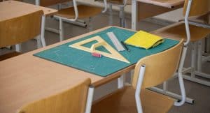 Classroom desk showcasing math tools such as a ruler and set square, along with an eraser and cleaning cloth on a cutting mat.